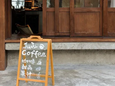 溫馨木牆咖啡店，櫥窗展示與舒適座位區，包含餐桌與沙發，場景中散落杯碗