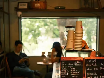 溫馨親切的餐廳內部，設有木質吧台與座椅，三人正熱絡交談