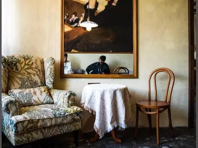 Cozy living space with a large painting above a table, two chairs, and a dining table, creating a warm and inviting atmosphere
