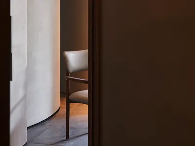 A cozy living space with a wooden chair and a doorway leading to another room, suggesting a warm and inviting atmosphere