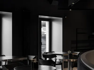 Modern restaurant interior with black walls, dining tables, and chairs, creating a stylish and inviting atmosphere
