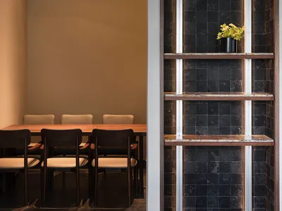 A well-lit dining area with a long table and multiple chairs, surrounded by modern architecture-inspired design
