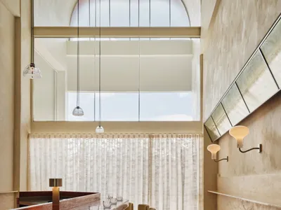 Spacious modern restaurant interior with a long wooden bar counter and several chairs, creating a welcoming atmosphere