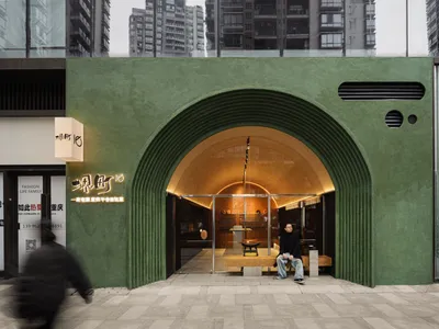 A bustling Asian restaurant with green walls, an archway entrance, and patrons enjoying meals on benches and chairs