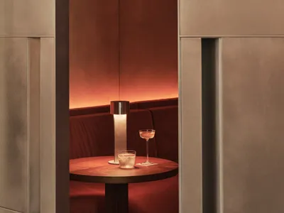 A dimly lit room with a wooden table, wine glasses, and a bottle of wine, surrounded by chairs in a relaxing and intimate atmosphere