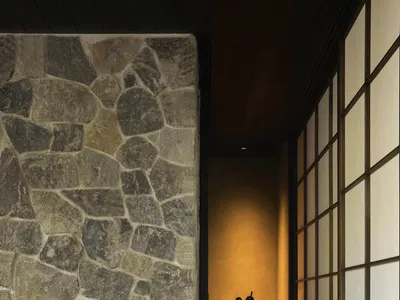 Cozy bathroom with a stone wall, a vase with yellow flowers, a bathtub, and two bottles