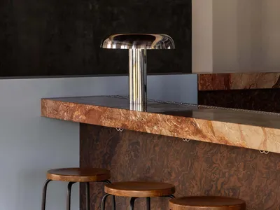 A modern bar with a marble countertop and wooden stools, inviting and comfortable atmosphere for socializing and enjoying drinks