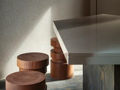 A dining table surrounded by four wooden stools, with two chairs on each side, creating a cozy seating arrangement in a modern yet warm space