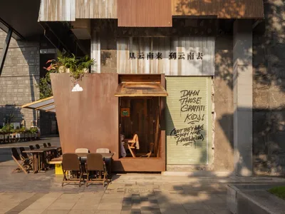 A restaurant with a unique blend of traditional Chinese and modern Western architectural styles, featuring a large wooden structure, metal accents, and potted plants, creating a warm and inviting atmosphere