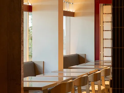 Modern restaurant dining area with glass tables, white walls, and dim lighting creating a cozy atmosphere