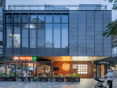 現代玻璃立面餐廳，木質點綴與金屬元素，搭配盆栽、桌椅與電視，營造時尚舒適氛圍