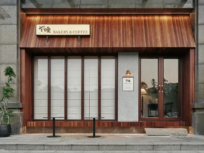 木質外觀的烘焙咖啡店，配有兩張餐桌、椅子與盆栽，背景明亮