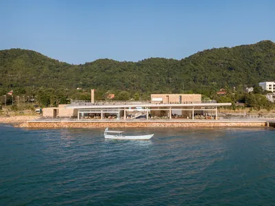 A beachside restaurant with a large open dining area, featuring various chairs and a scenic ocean view
