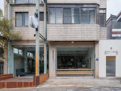 餐廳內部有多張餐桌椅，周圍環繞磚造建築與大片窗戶