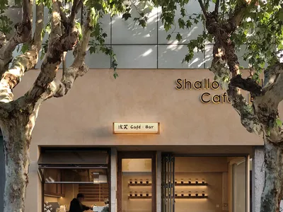 Cozy Asian restaurant with a wooden exterior and interior, featuring a dining area with chairs and a potted plant near the entrance