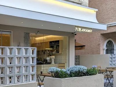 A modern Asian restaurant with a large window allowing natural light, featuring chairs, decorative items, and a variety of objects on display