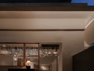 白色餐廳建築搭配黑色屋頂，由兩盞外牆燈光照亮，營造夜晚溫馨氛圍