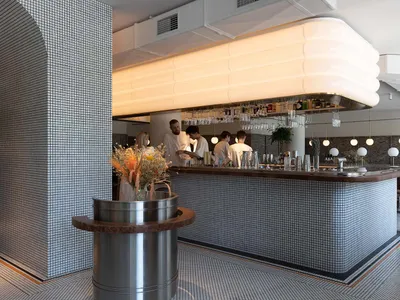 A modern restaurant bar with a countertop, wine glasses, and bottles displayed in a sophisticated and inviting atmosphere