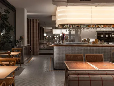 A restaurant interior with a bar area and tables, featuring bottles and comfortable seating for socializing and dining