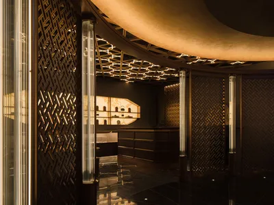 A modern hotel lobby with a high ceiling, artworks on the walls, two chairs, and decorative vases, creating a welcoming atmosphere