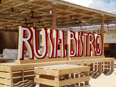 Casual outdoor restaurant with a wooden structure, benches, and a sign reading Rush Bistro