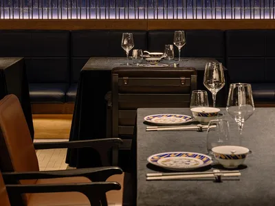 A modern restaurant interior with glass block walls, tables, chairs, and wine glasses, creating a stylish and inviting atmosphere