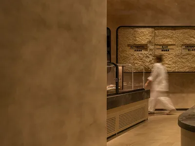 A woman walks past a kitchen counter in a casual dining restaurant with signs on the wall and a warm atmosphere