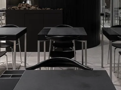 A modern restaurant interior with black tables and chairs, multiple dining tables and chairs in a stylish and inviting space