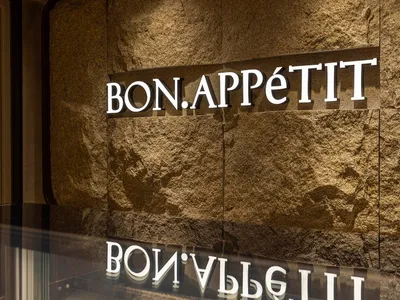 A restaurant interior with a stone wall and a sign reading Bon Appetit, creating a warm and inviting atmosphere
