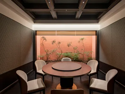 A modern dining space with a round wooden table, three chairs, and red brick and white painted walls creating a cozy atmosphere