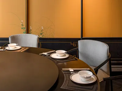Elegant dining space with gray chairs, a black table, white plates, and decorative vases