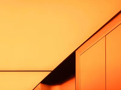 A hotel corridor with orange walls, two sinks, mirrors, and trash cans, suggesting a clean and well-maintained environment