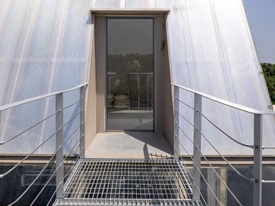 Casual outdoor living area with a metal staircase, a doorway, and two people standing near the stairs
