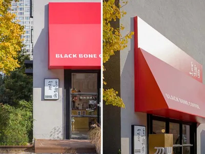 灰色店面融入亞洲設計元素，紅黑遮陽篷與盆栽點綴現代都市景觀