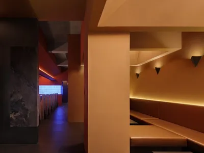 橘色牆面搭配木質長椅與餐桌，營造溫暖舒適的走廊氛圍，歡迎賓客