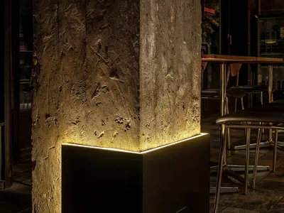 光線充足的客廳空間，配有黑色金屬立柱、座椅與盆栽植物，營造溫暖氛圍