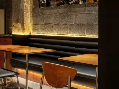 A restaurant interior with multiple dining tables, chairs, and a couch, creating a warm and inviting atmosphere