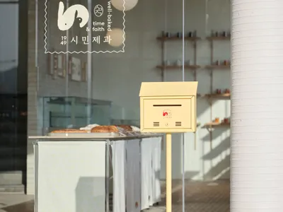 一間溫馨的麵包店，配有玻璃窗、展示商品，以及店外黃色信箱