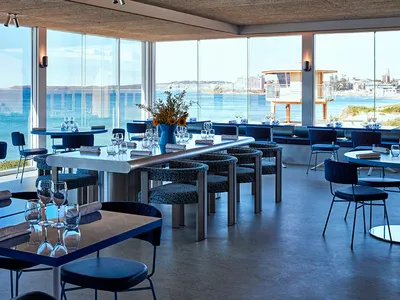 A spacious restaurant dining area with various chairs, some with cushions, and wine glasses on tables, set in a relaxed and inviting atmosphere