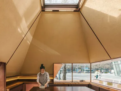 休閒餐廳內部，設有餐桌、椅子與採光窗戶，場景中有兩人出現