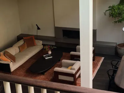 A cozy living area with a couch, chairs, dining table, and potted plants, set against a neutral background