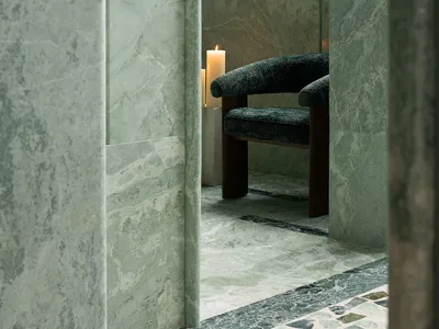 Bathroom with a shower stall containing a wooden chair with a black seat and two candles on the floor for a cozy ambiance
