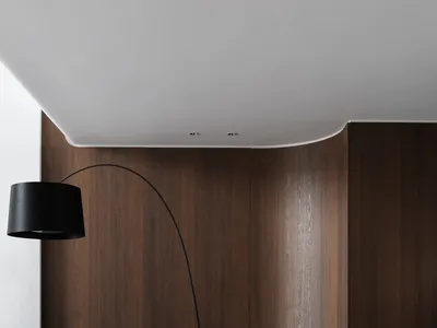 Cozy living area with a couch, chair, and lamp, surrounded by wooden panel walls and illuminated by a prominent lamp
