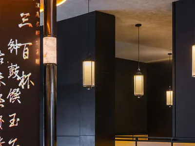 舒適亞洲餐廳內部，黑牆、餐桌、椅子，桌上擺放各式杯碗
