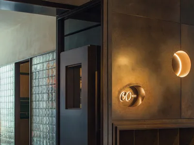 Hotel lobby with tile walls, a doorway leading to another room, a clock on the wall, and a modern atmosphere
