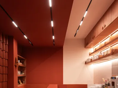 紅牆橘色檯面、餐桌、椅子、家電，以及檯面上多個杯子的現代廚房