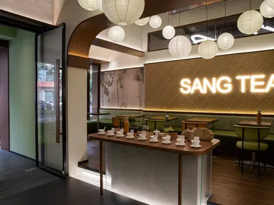 Inviting restaurant interior with a bar, tables, chairs, potted plants, and hanging lights