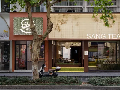 A modern Asian restaurant with orange walls, natural light, and comfortable seating for customers