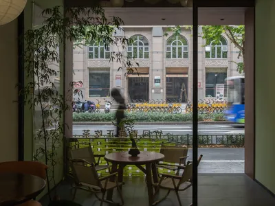 A casual dining area with a wooden table and chairs, surrounded by bicycles outside, in a restaurant or cafe setting