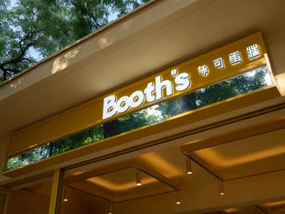 A well-lit Asian restaurant with yellow walls, a large window, and sunlight streaming in, surrounded by trees outside